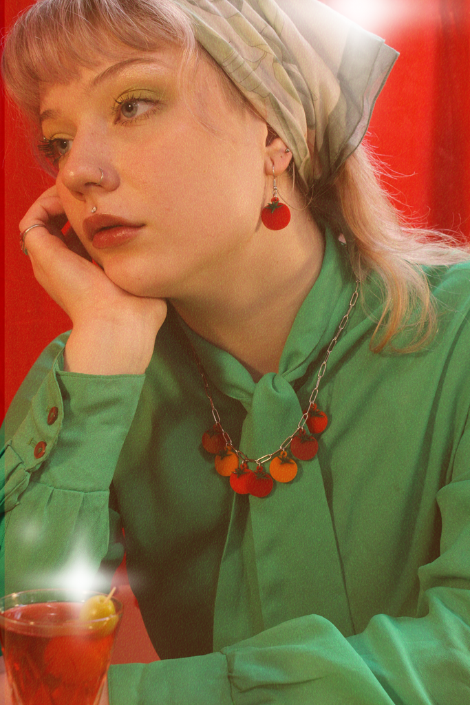 Model wearing stainless steel oval link necklace featuring seven red and orange tomato pendants with the matching earrings