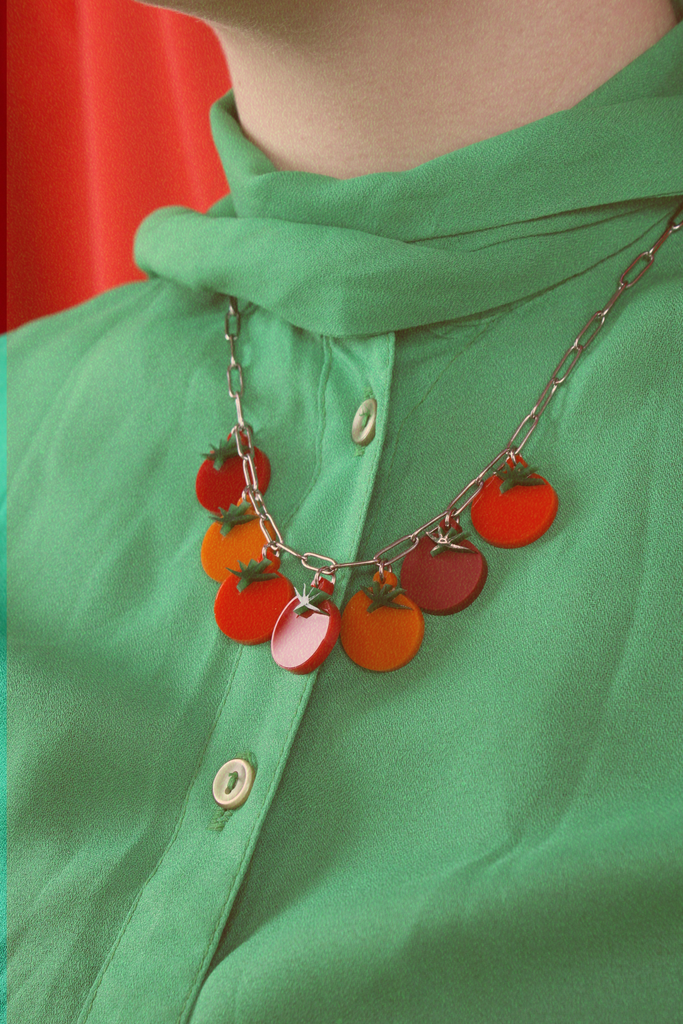 Model wearing stainless steel oval link necklace featuring seven red and orange tomato pendants with the matching earrings