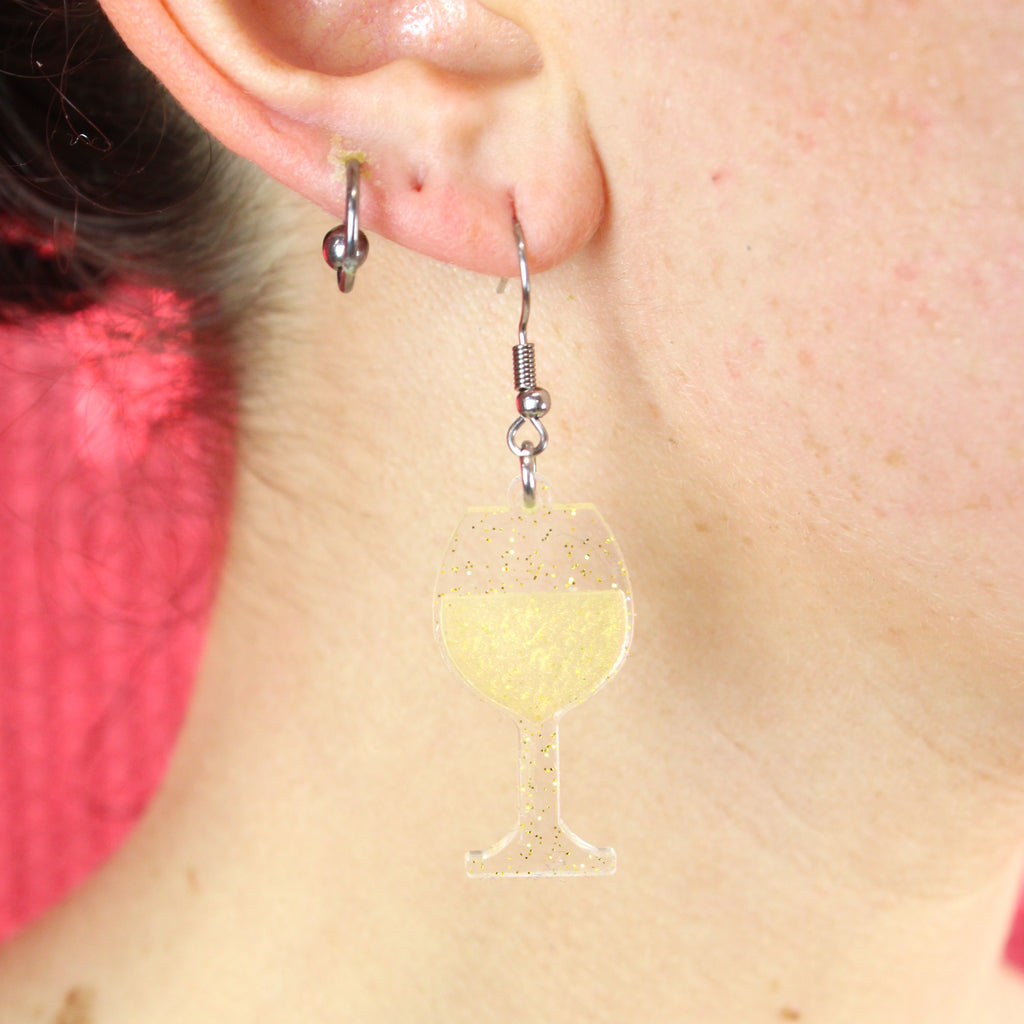 Model wearing earrings that feature a glass of sauvignon blanc on stainless steel earwires