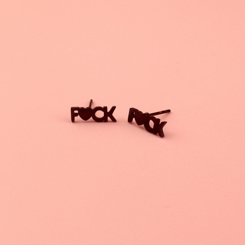 Black stud earrings with the word F*CK, the U being replaced with a heart