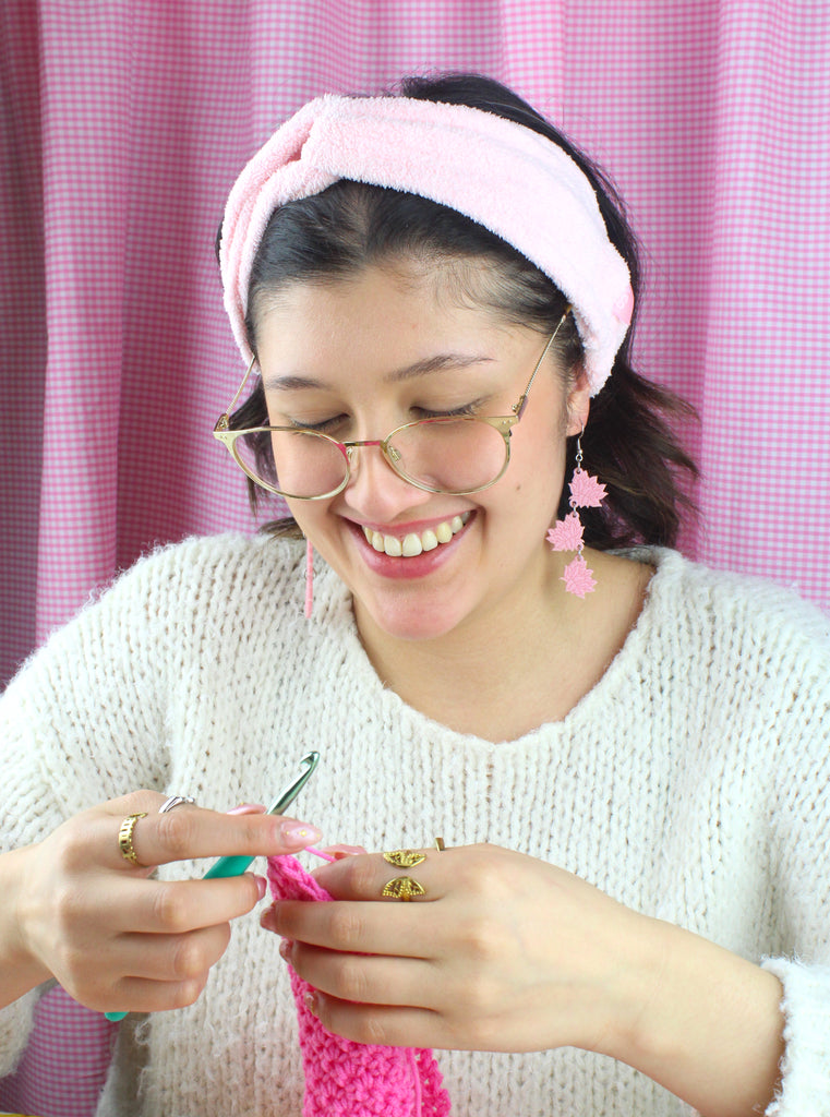 Model wearing Pink acrylic cascading lotus flower charms on stainless steel earwires. Model is seen crocheting.