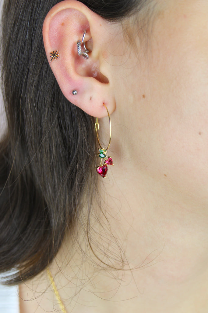 Ear wearing gold plated stainless steel hoops with glass cherry charms