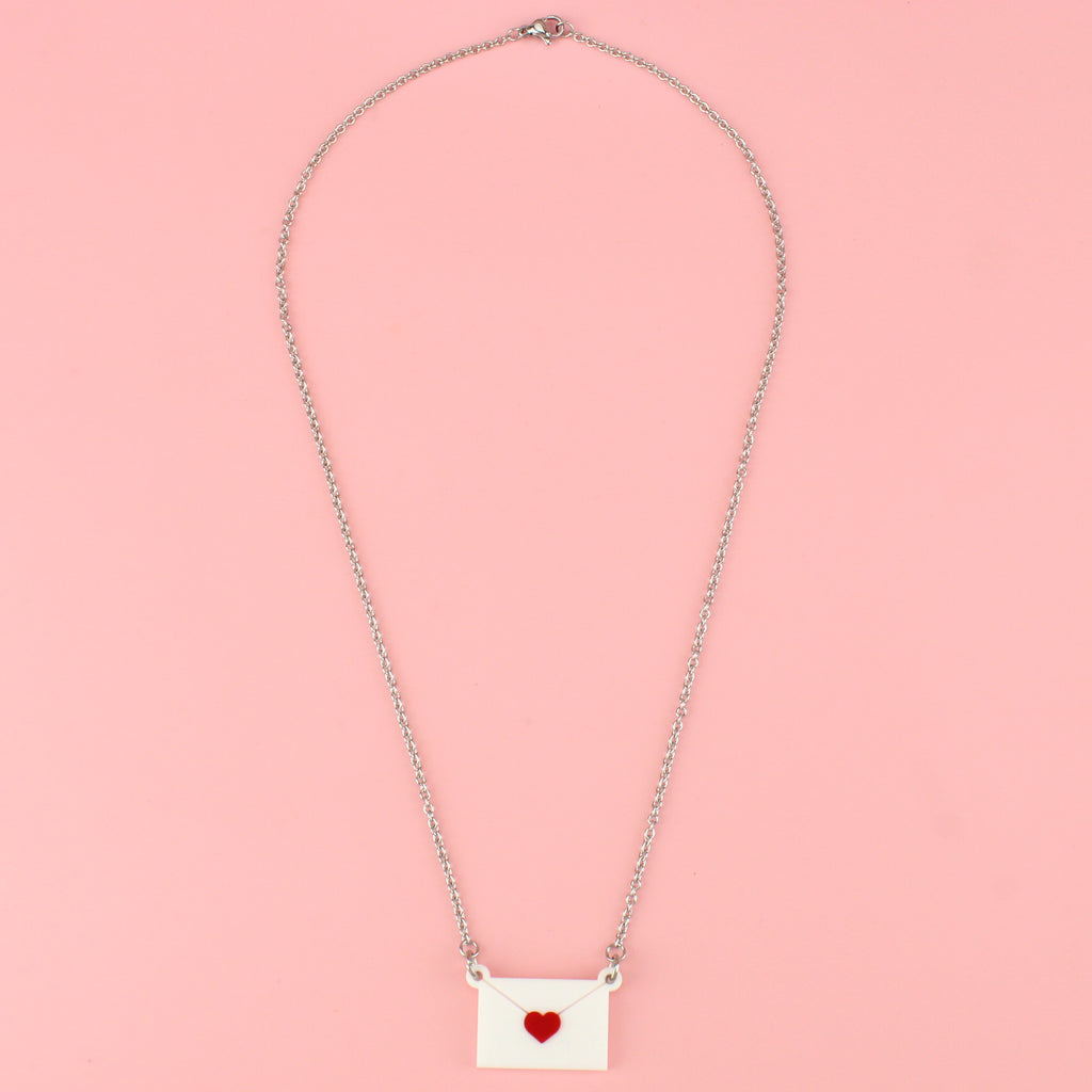 love letter pendant featuring a white envelope sealed with a red heart on a stainless steel chain. 