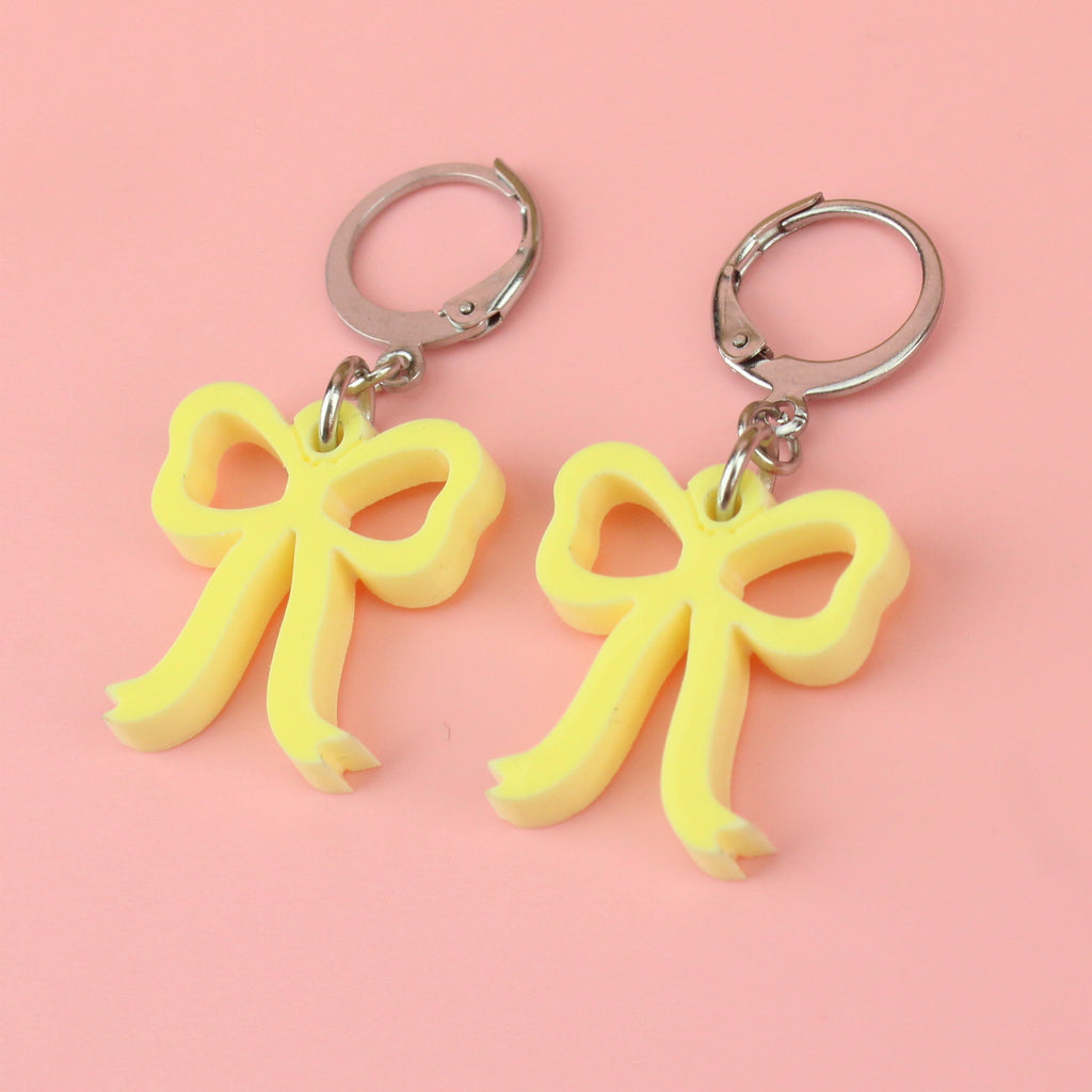Baby yellow bow charms on stainless steel huggie hoops