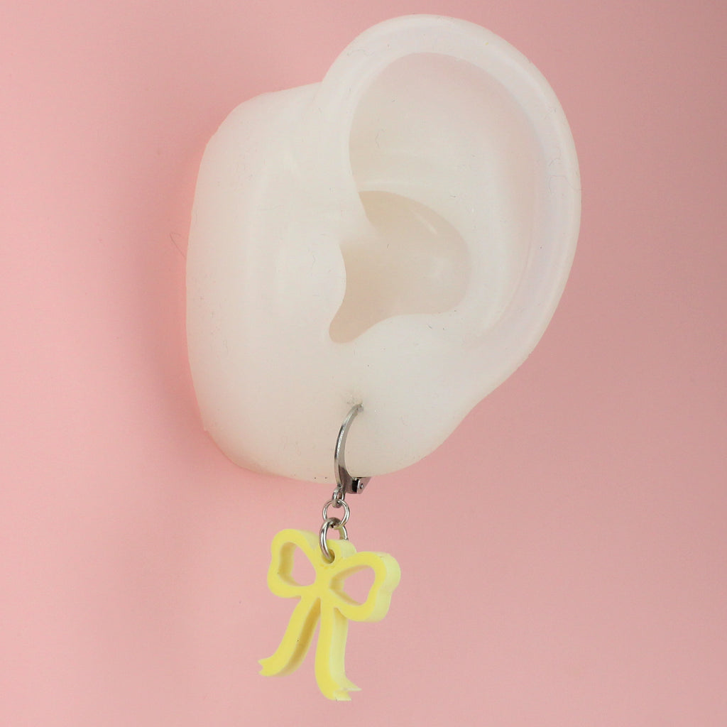 Ear wearing Baby yellow bow charms on stainless steel huggie hoops