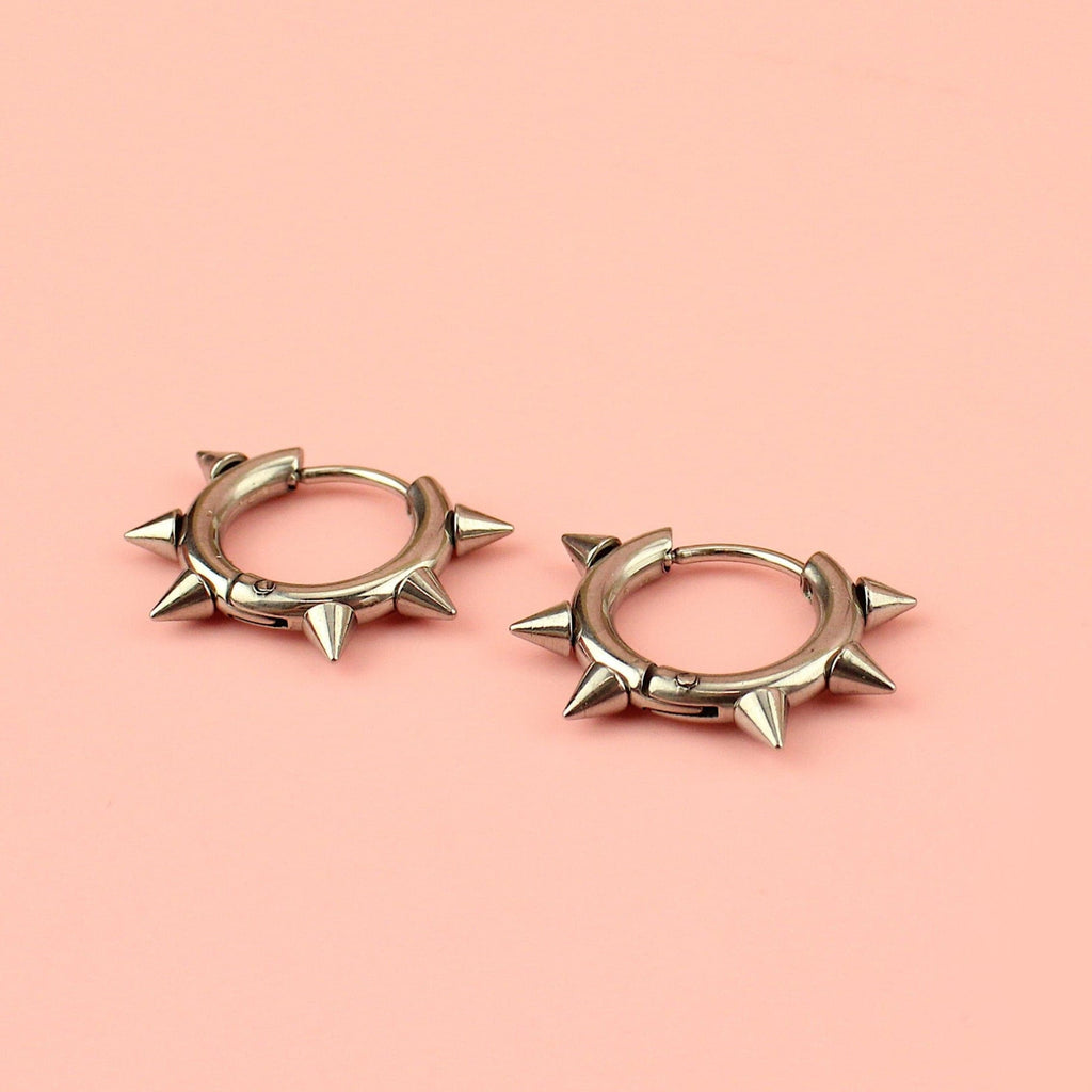 Stainless steel huggie hoops with punk-inspired spikes surrounding the edge 