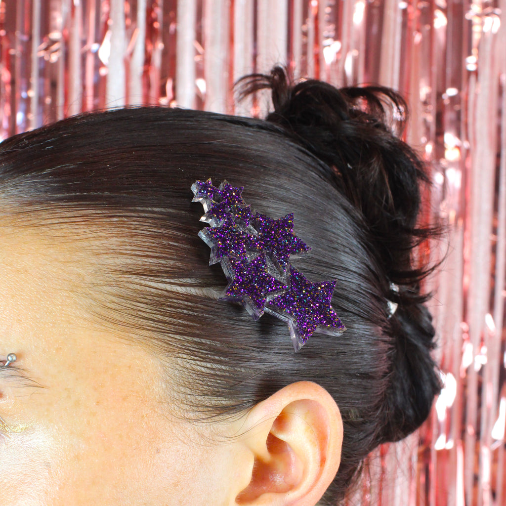 Model wearing a hair clip made up of a cluster of purple glittery stars