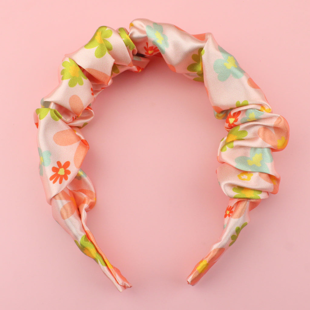 Satin scrunchie style headband with a pink floral design featuring blue, red, green and orange flowers