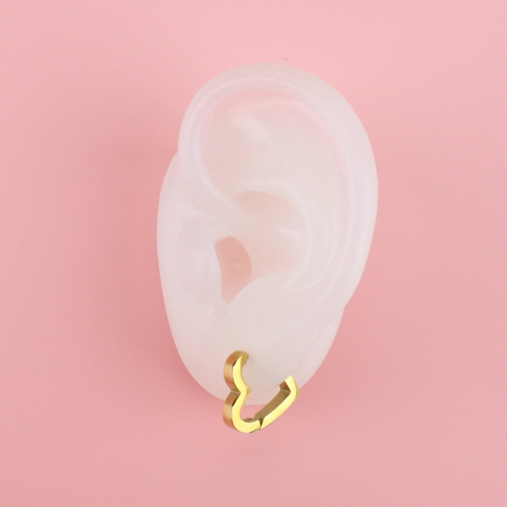 Ear showing Gold Plated Stainless Steel heart shaped huggie hoop earrings