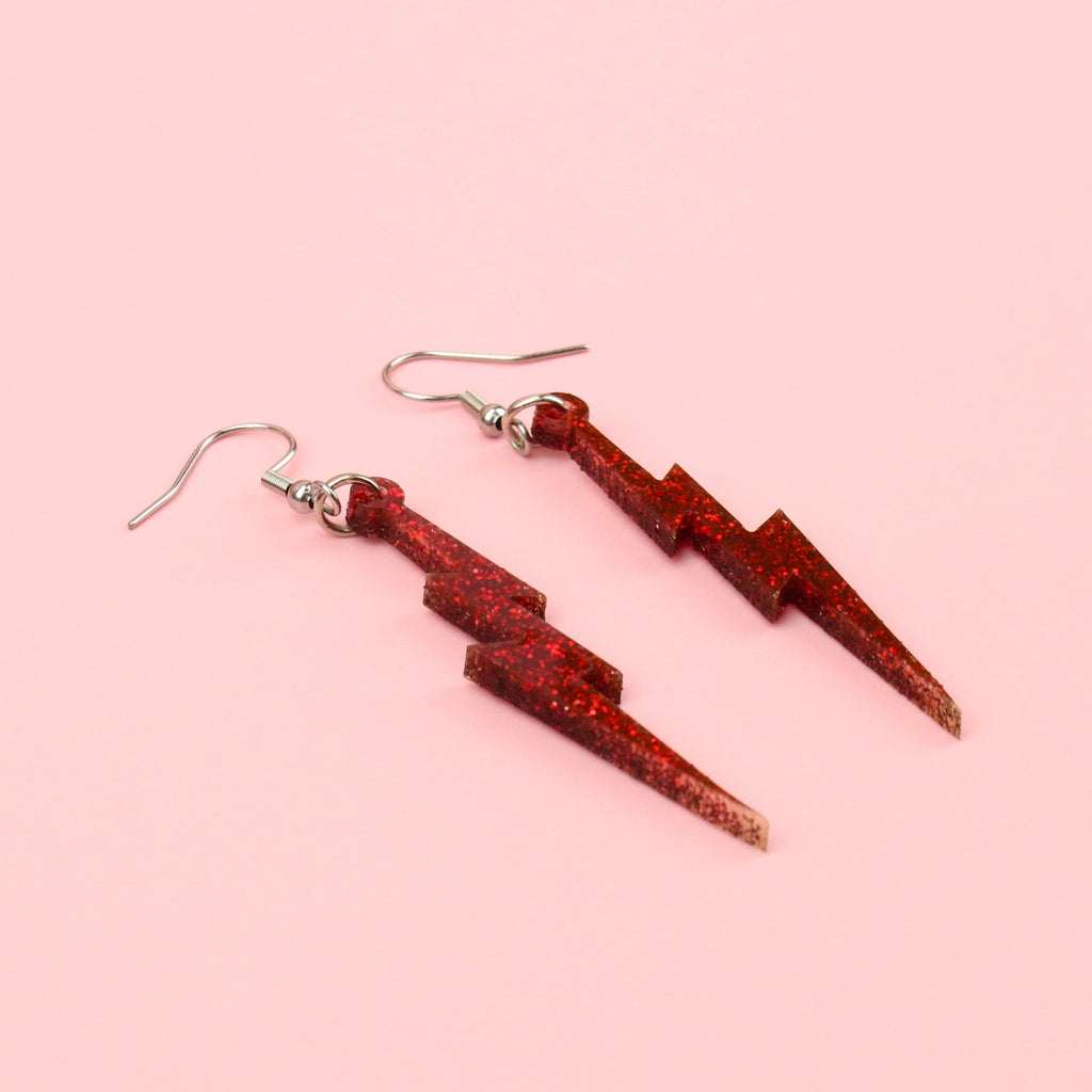 Laser cut red glitter perspex earrings with a lightning bolt design on stainless steel earwires