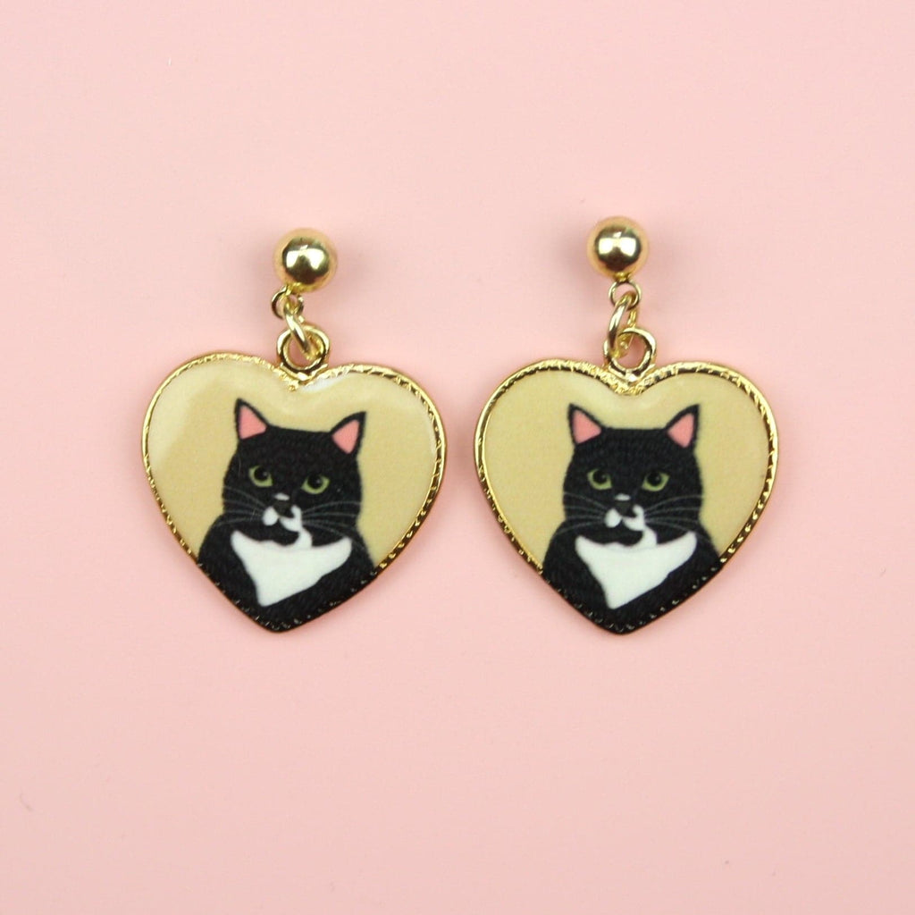 Gold heart shaped charms with a black cat portrait inside them on gold plated stainless steel studs