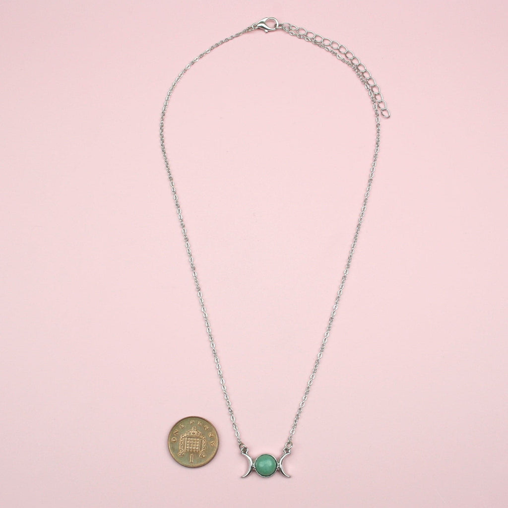 Green Aventurine Charm with 2 Crescent Moons either side of it on a Stainless Steel chain with a penny next to the charm for scale