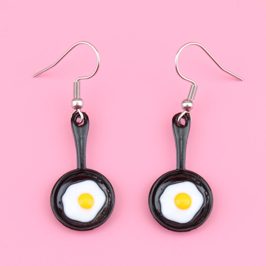 Charms that feature a fried egg in a frying pan on stainless steel earwires