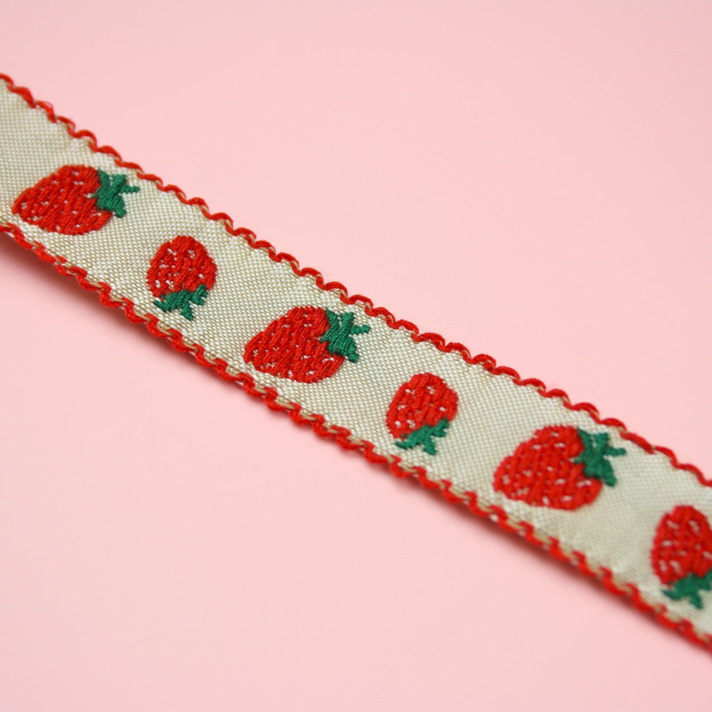 A strawberry print design on a white fabric choker with red edges 