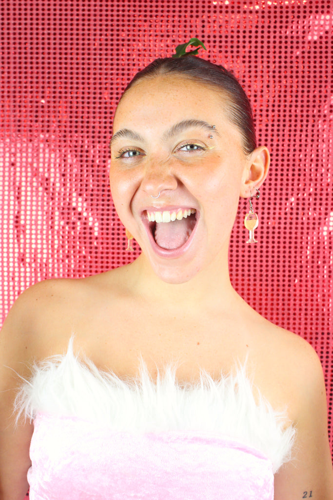 Model wearing earrings that feature a glass of sauvignon blanc on stainless steel earwires