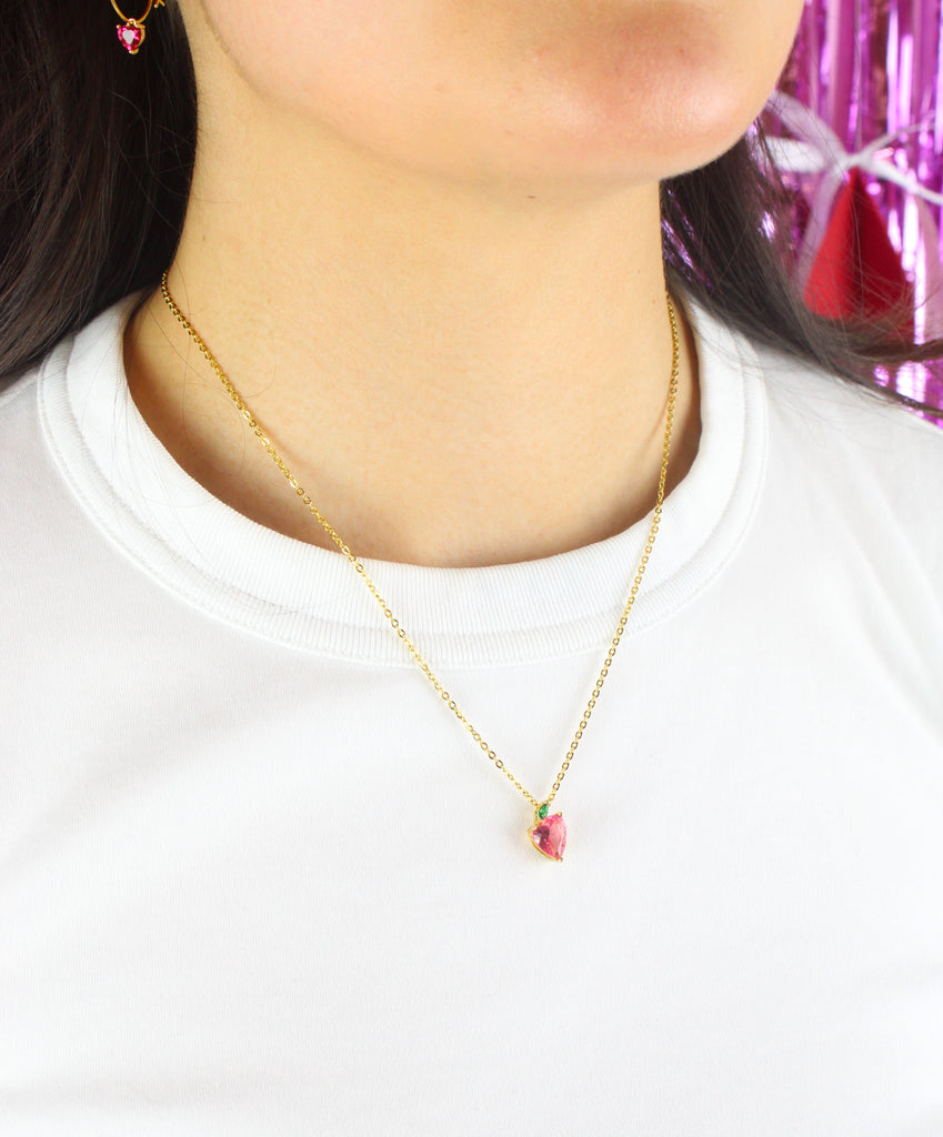 Model wearing gold plated stainless steel necklace with a glass effect red apple pendant