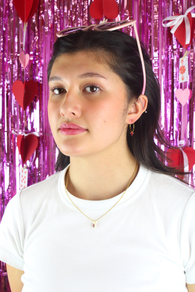Model wearing gold plated stainless steel hoop with a red glass-effect heart charm