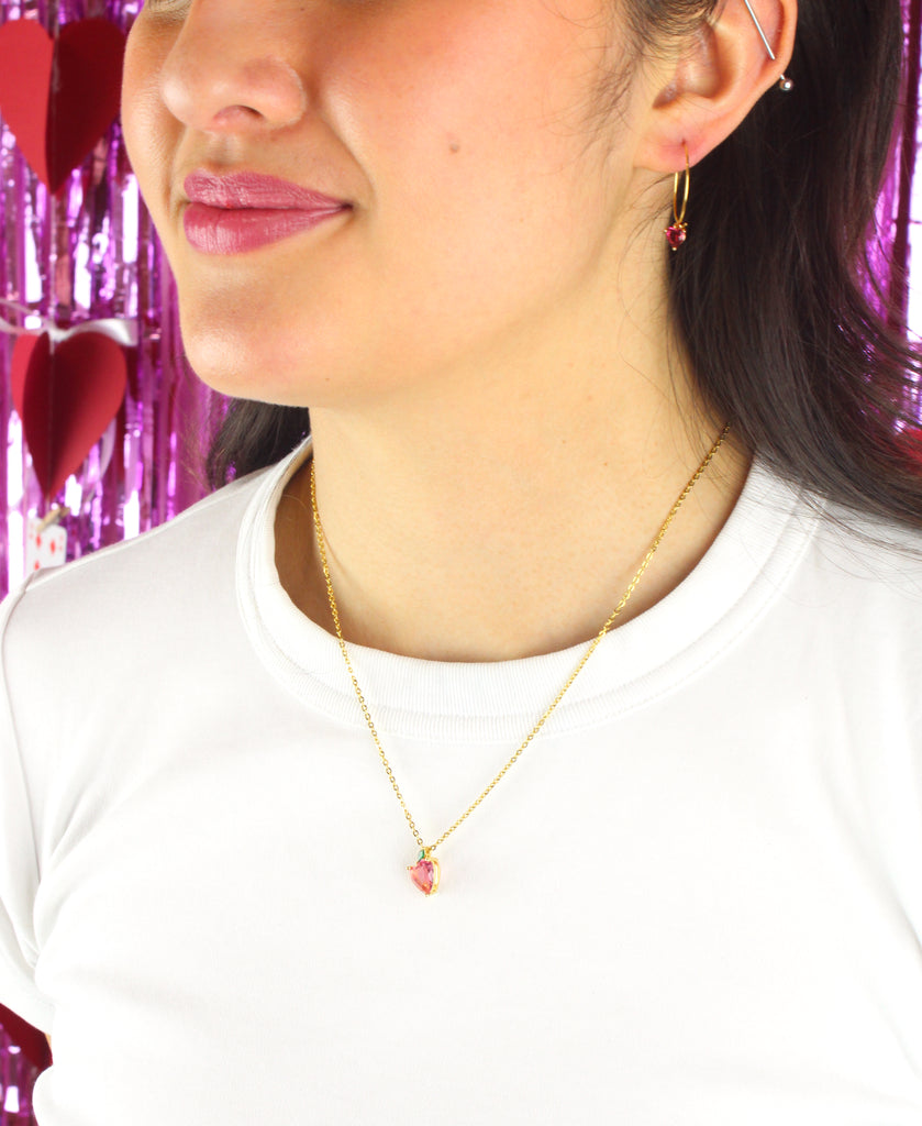 Model wearing gold plated stainless steel chain with a small red heart glass-effect pendant