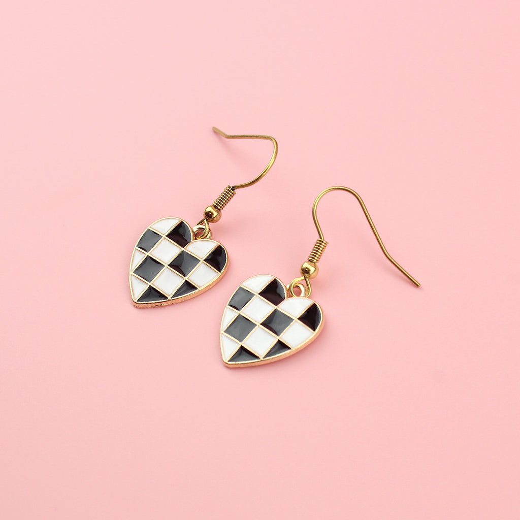 Black and white base metal charms with black and white enamel checkerboard design in the shape of a heart on gold plated stainless steel earwires