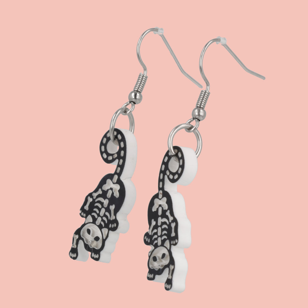 Model wearing cat skeleton charms on stainless steel earwires 