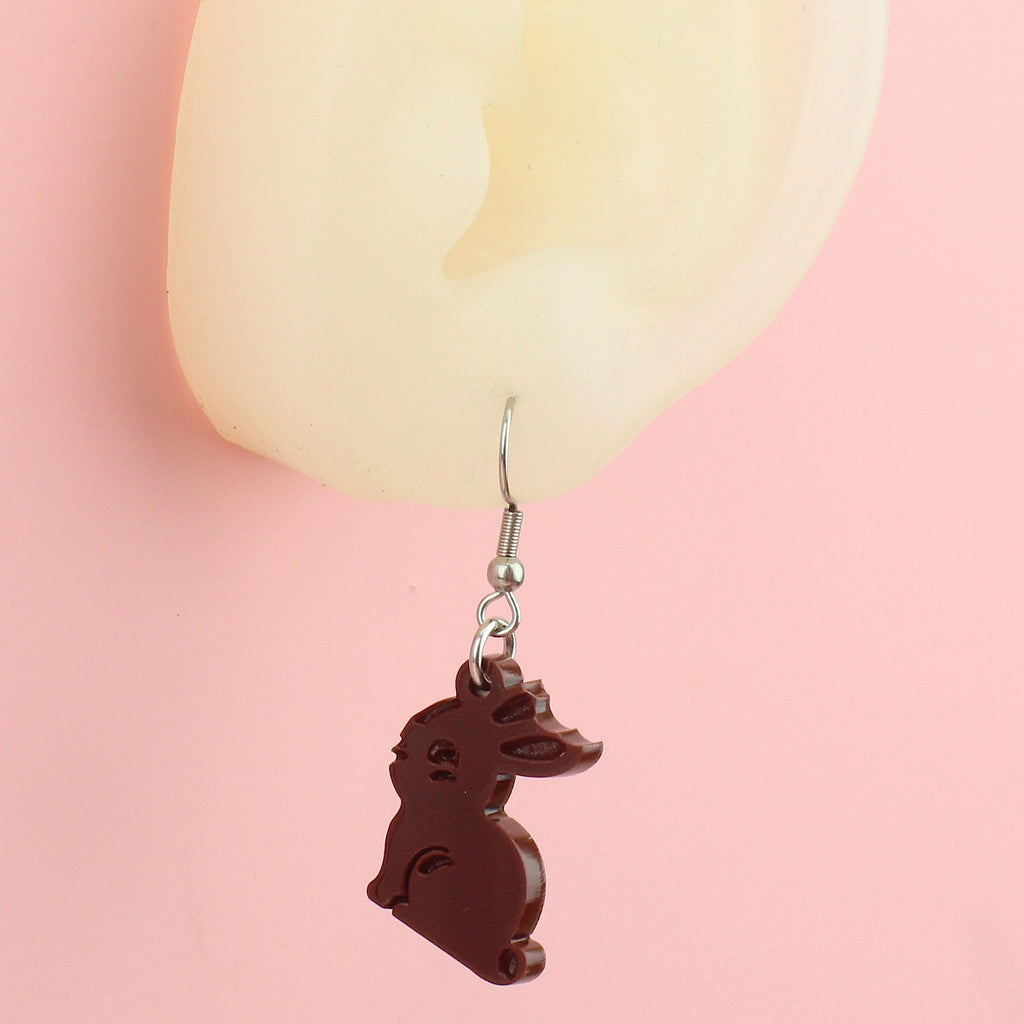 Ear wearing charms in the shape of chocolate bunnies with a bite taken out of one ear on stainless steel on stainless steel earwires
