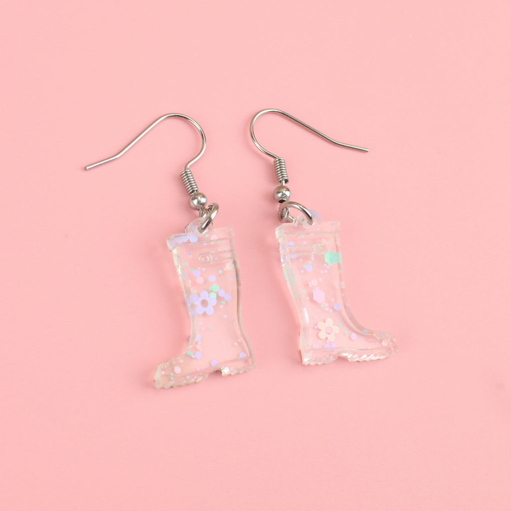 Transparent wellie boot charms with pieces of confetti and pastel flowers inside on stainless steel earwires