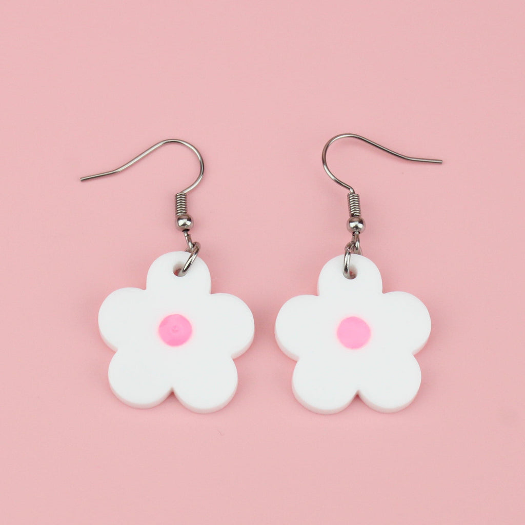 White perspex daisy charms with a pink glow in the dark resin centre on stainless steel earwires
