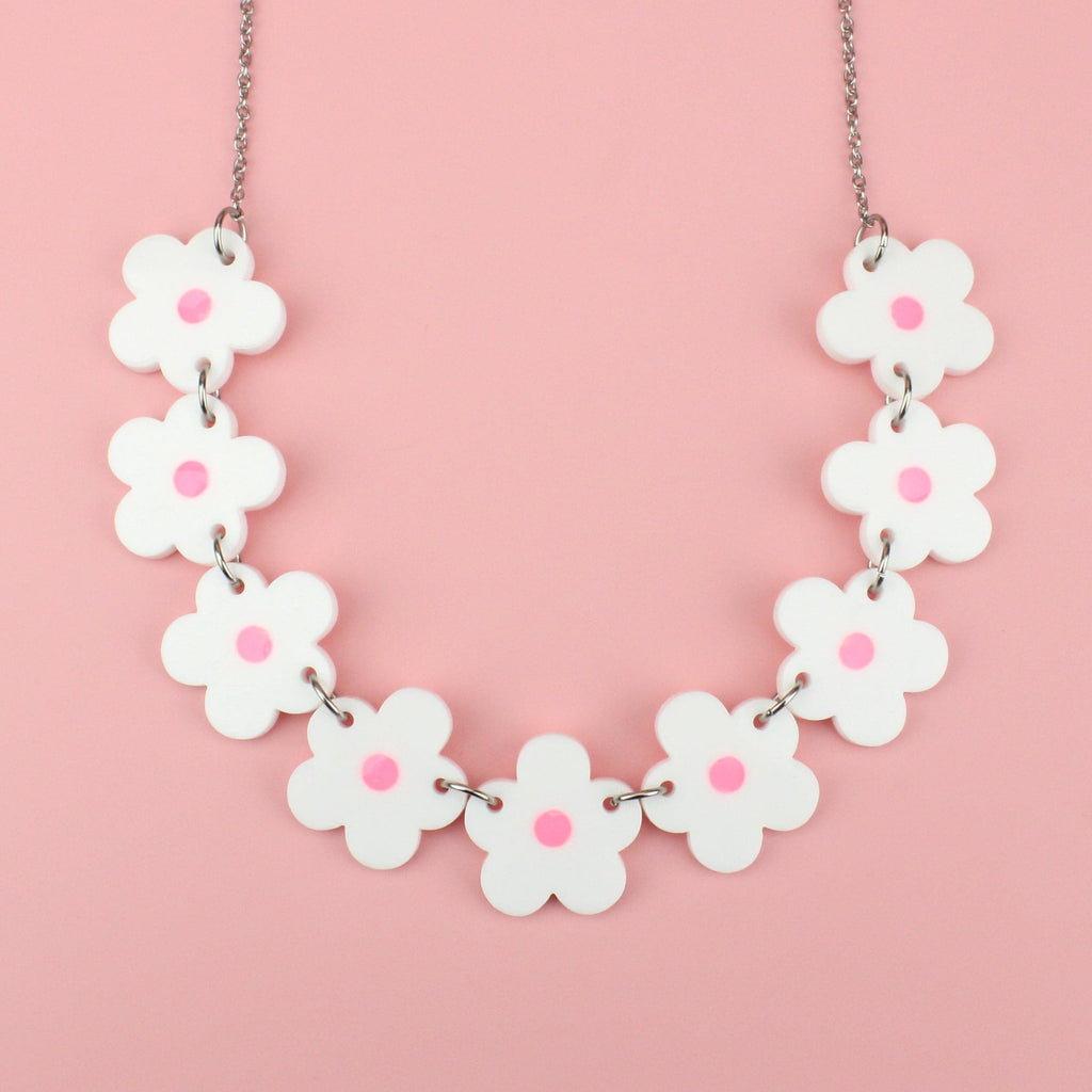 Nine white perspex flowers with a pink glow in the dark centre on a stainless steel chain