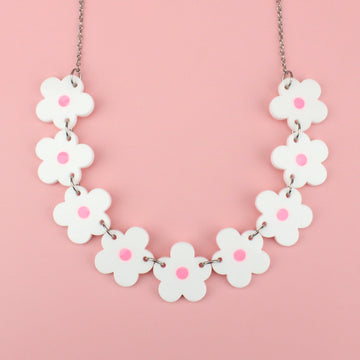 Nine white perspex flowers with a pink glow in the dark centre on a stainless steel chain