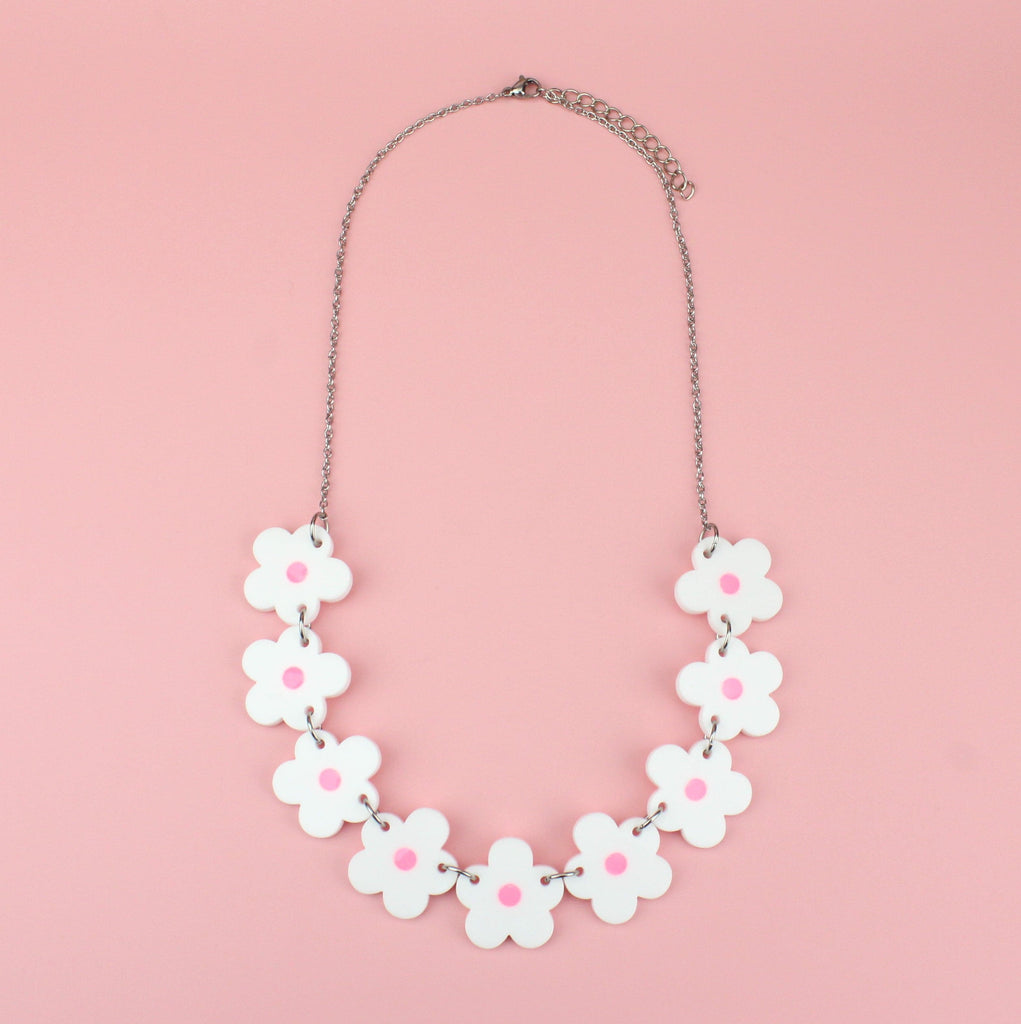 Nine white perspex flowers with a pink glow in the dark centre on a stainless steel chain