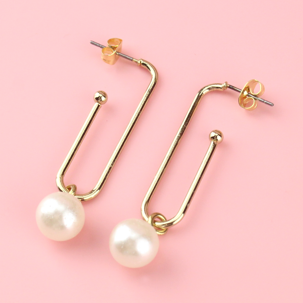 Gold plated earrings shaped similar to a paperclip wih pearl charms hanging from the bottom