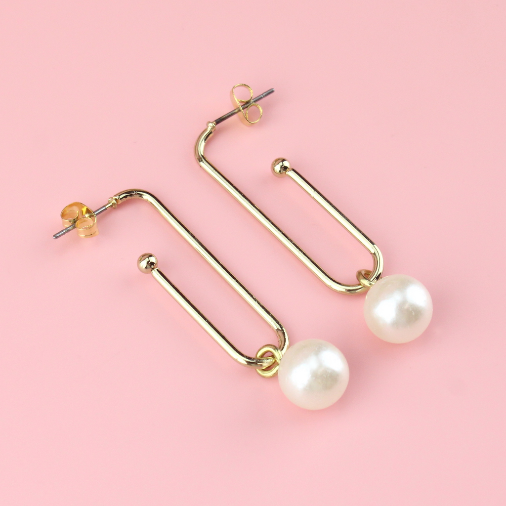 Gold plated earrings shaped similar to a paperclip wih pearl charms hanging from the bottom