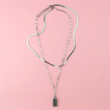 A layered necklace featuring both an oval link and snake chain with a rectangular pendant with emerald cubic zirconia stones