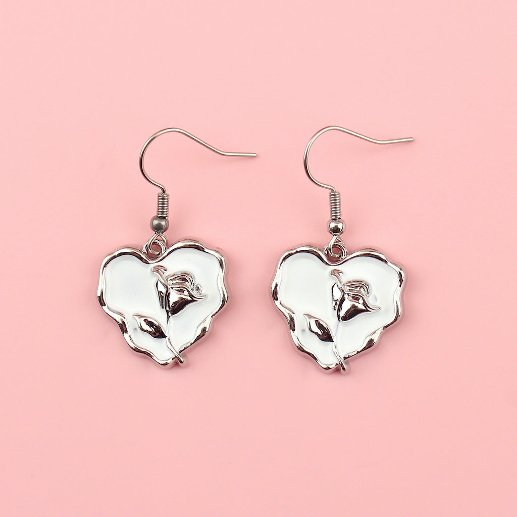 White heart charms with a silver outline and a silver rose in the middle on stainless steel earwires