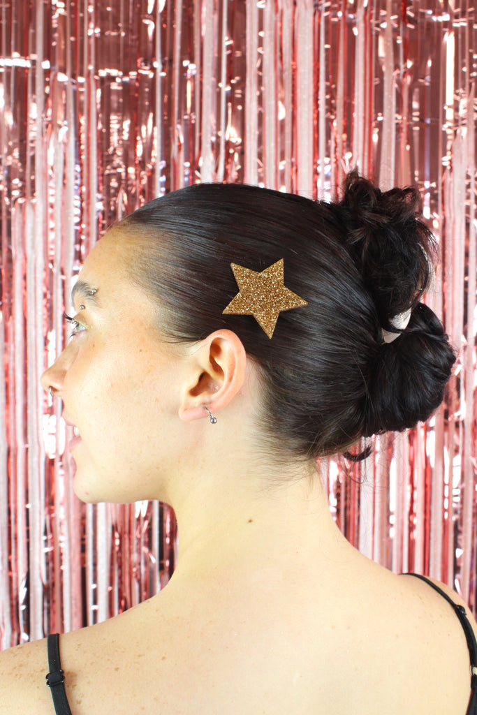 Model wearing a large gold glittery star hair clip