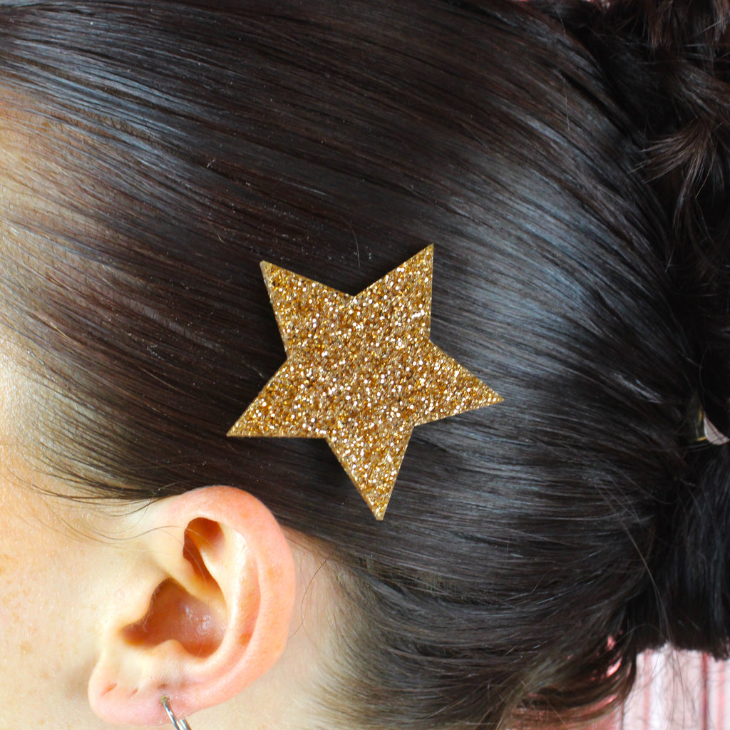 Model wearing a large gold glittery star hair clip