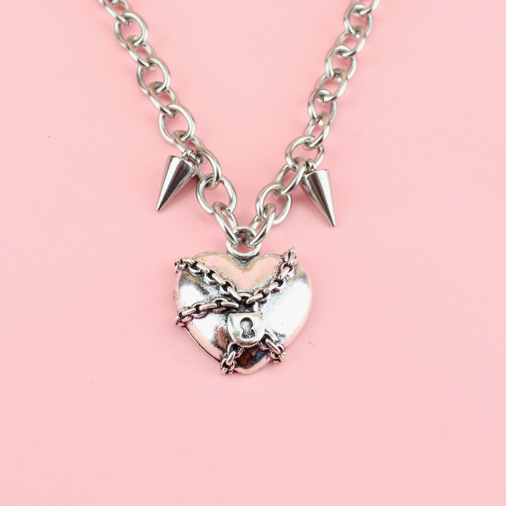 Heart pendant wrapped in chains featuring two spikes either side of the titanium chain