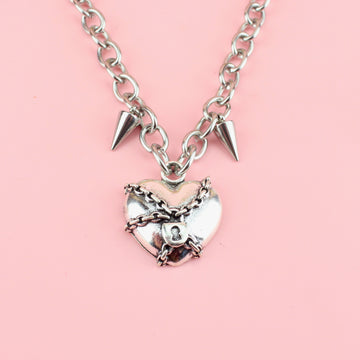Heart pendant wrapped in chains featuring two spikes either side of the titanium chain