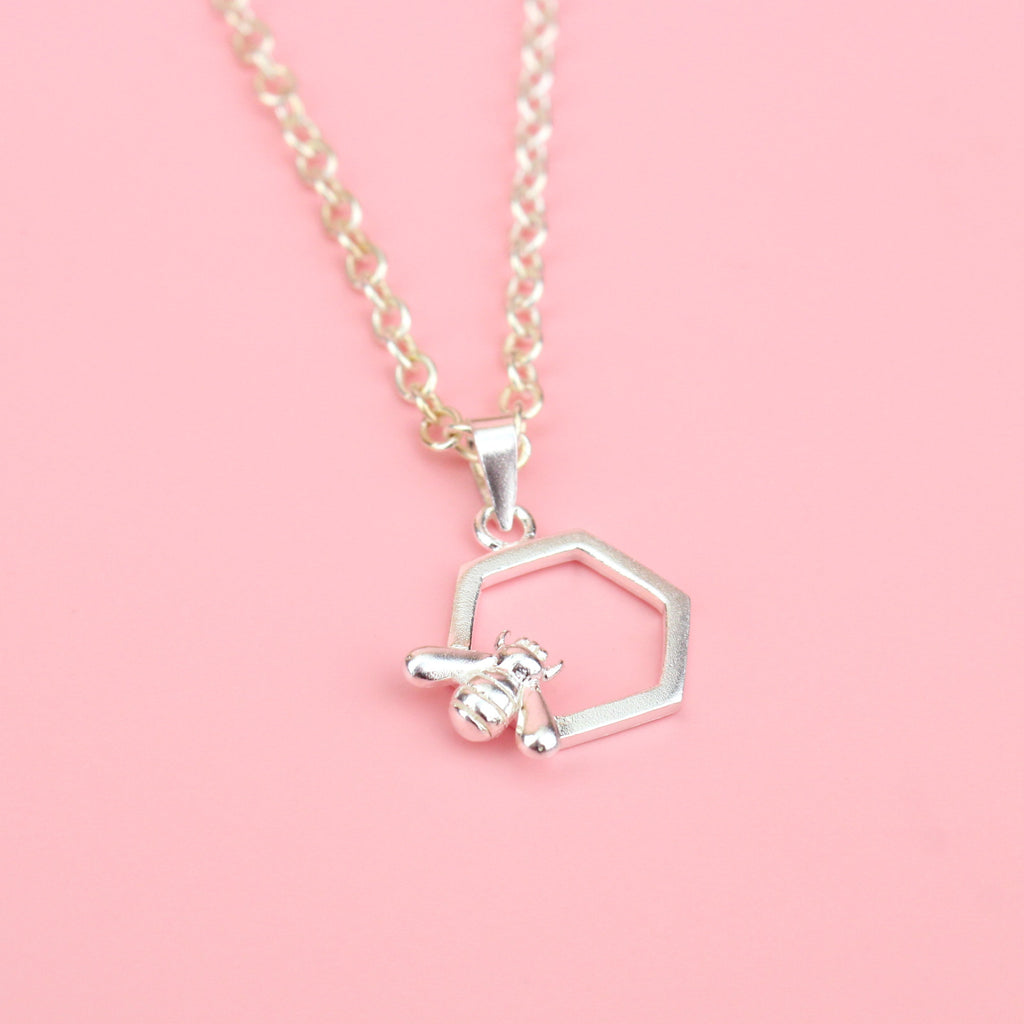 Sterling silver honeycomb charm with a bee perched on the bottom left corner, on a stainless steel chain