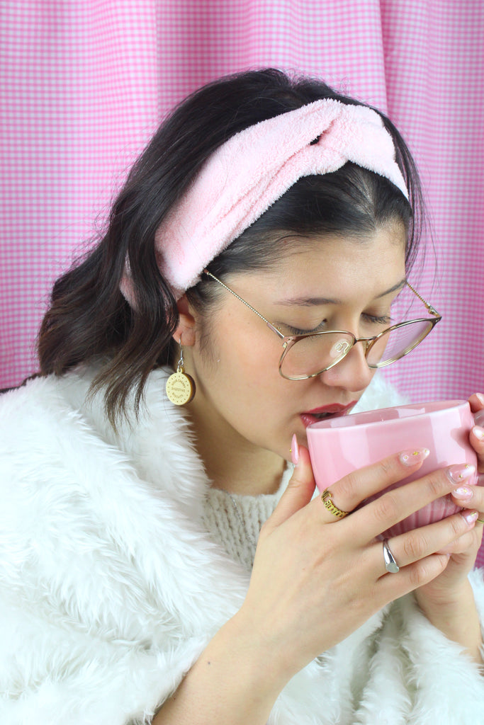 Model wearing Chocolate digestive charm reading 'Sour Cherry Digestive Biscuits' on a stainless steel earwire. Model is sipping a cup of tea.