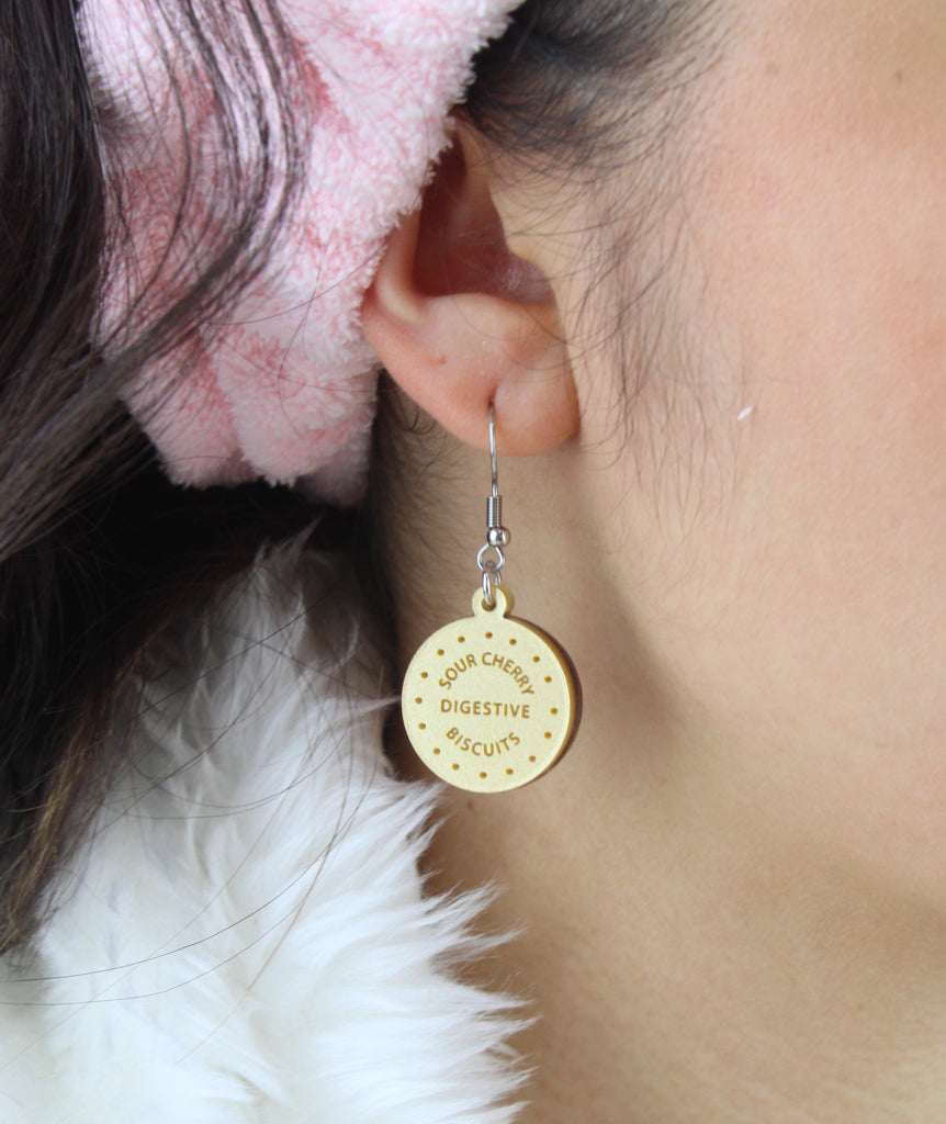 Model wearing Chocolate digestive charm reading 'Sour Cherry Digestive Biscuits' on a stainless steel earwire