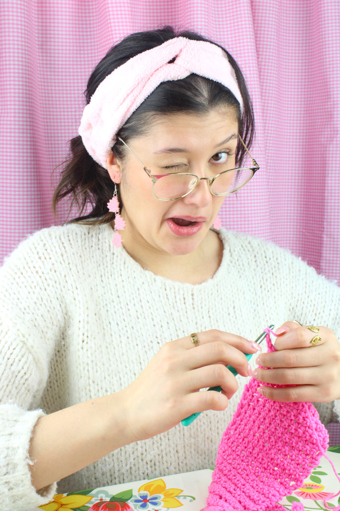 Model wearing Pink acrylic cascading lotus flower charms on stainless steel earwires. Model is seen crocheting.