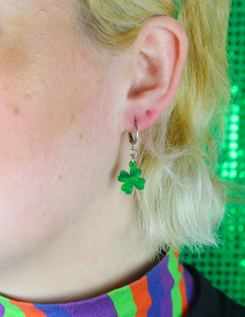 Model wearing Glittery four leaf clover charms on stainless steel huggie hoops