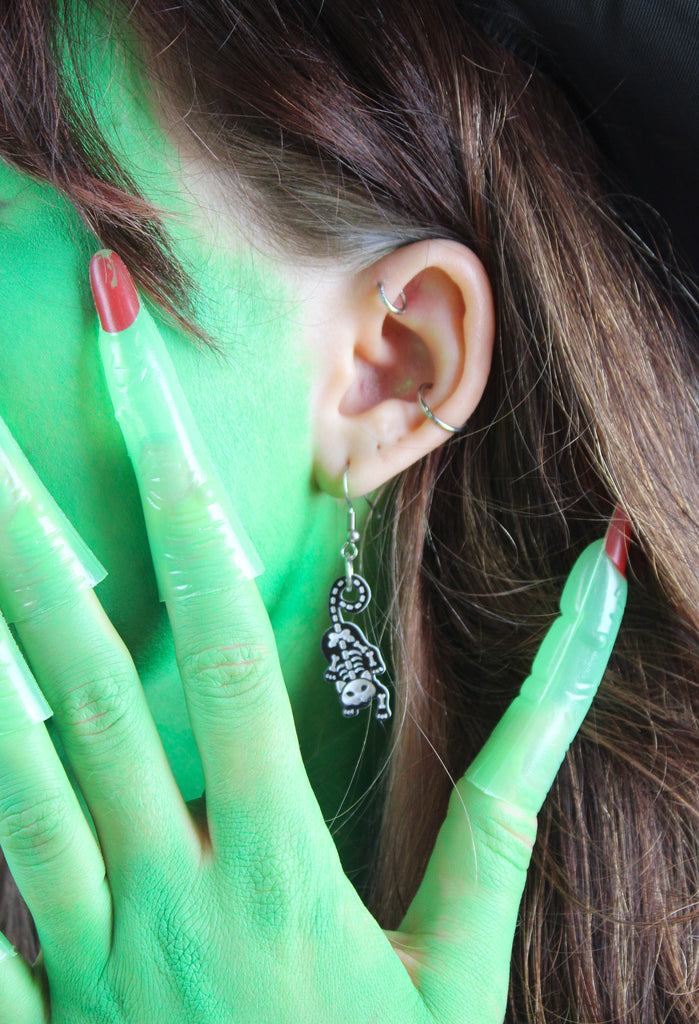 Model wearing cat skeleton charms on stainless steel earwires 