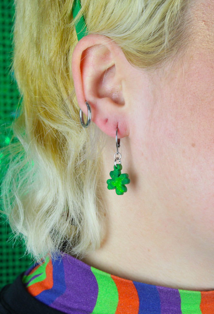 Model wearing Glittery four leaf clover charms on stainless steel huggie hoops