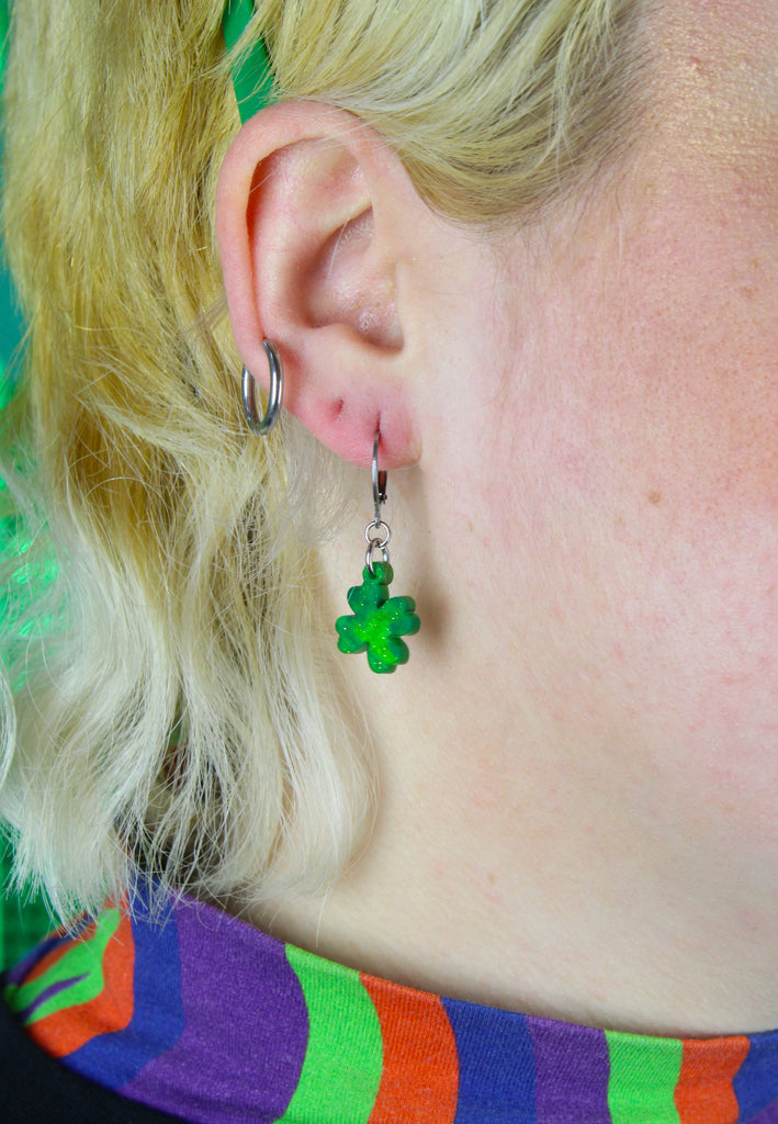 Model wearing Glittery four leaf clover charms on stainless steel huggie hoops