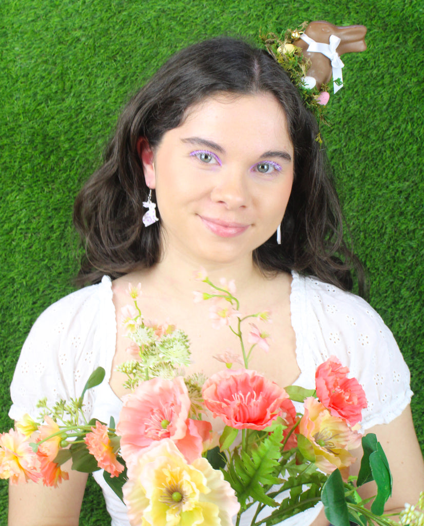 Model wearing white acrylic bunnies with hand-painted purple flowers on stainless steel earwires