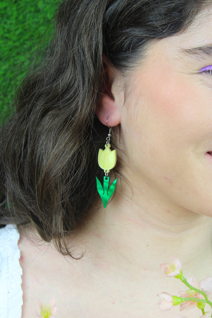 Model wearing Yellow acrylic tulip charms with green stems on stainless steel earwires