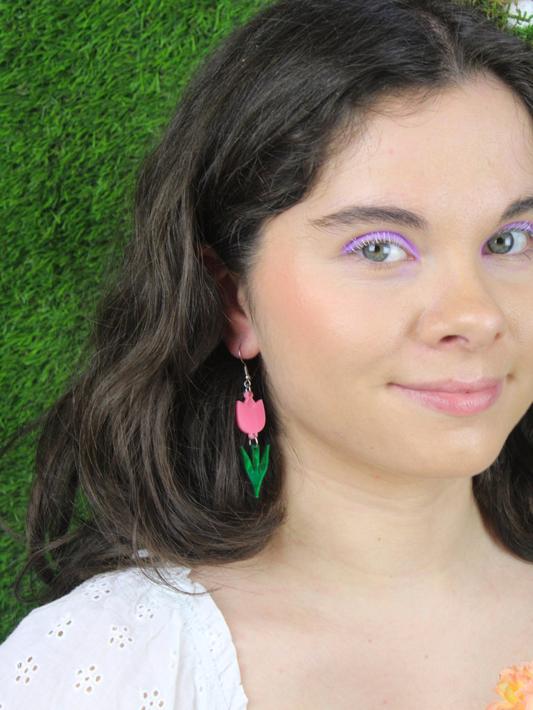 Model wearing Pink acylic tulip charms with green stems on stainless steel earwires