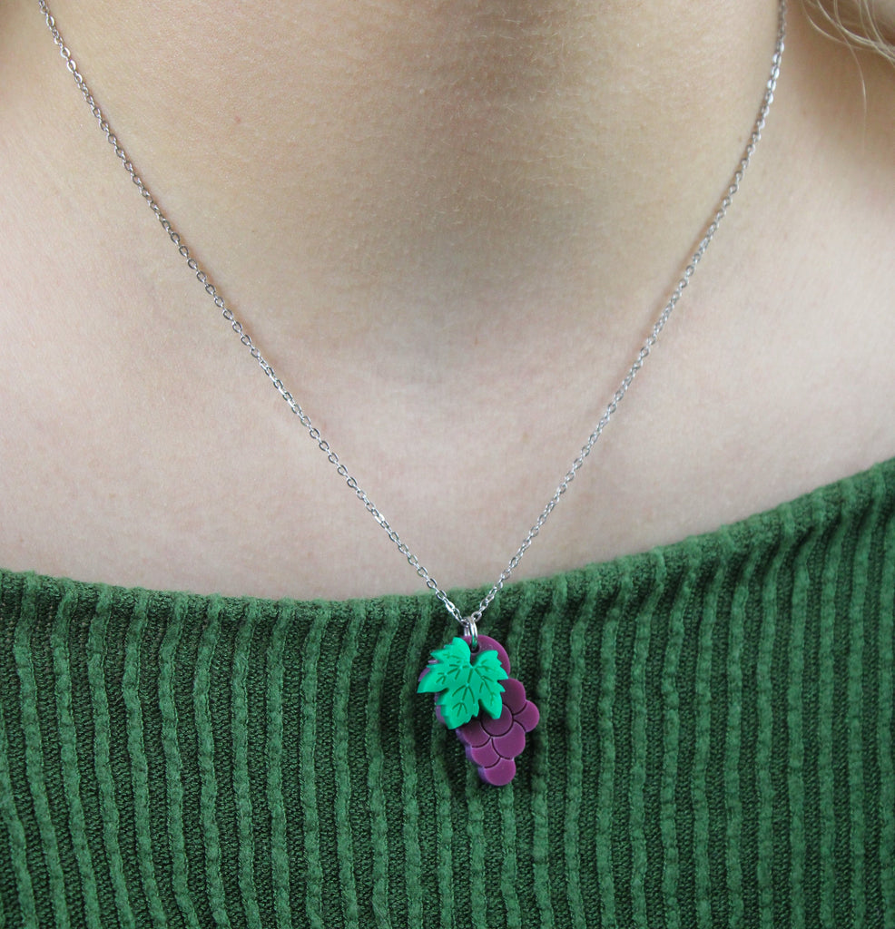Model wearing necklace featuring acrylic purple grapes on stainless steel chain